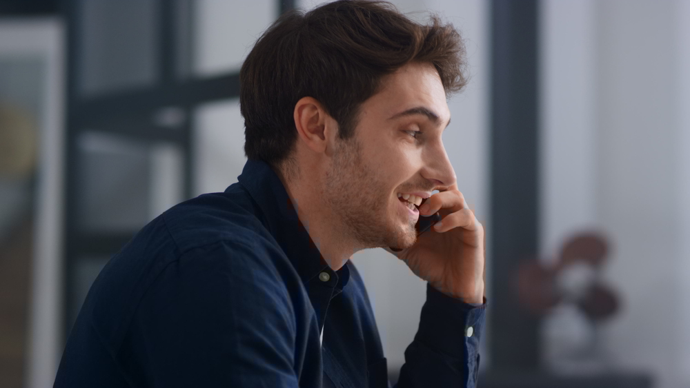 Closeup smiling man talking mobile in office. Cheerful guy having phone call