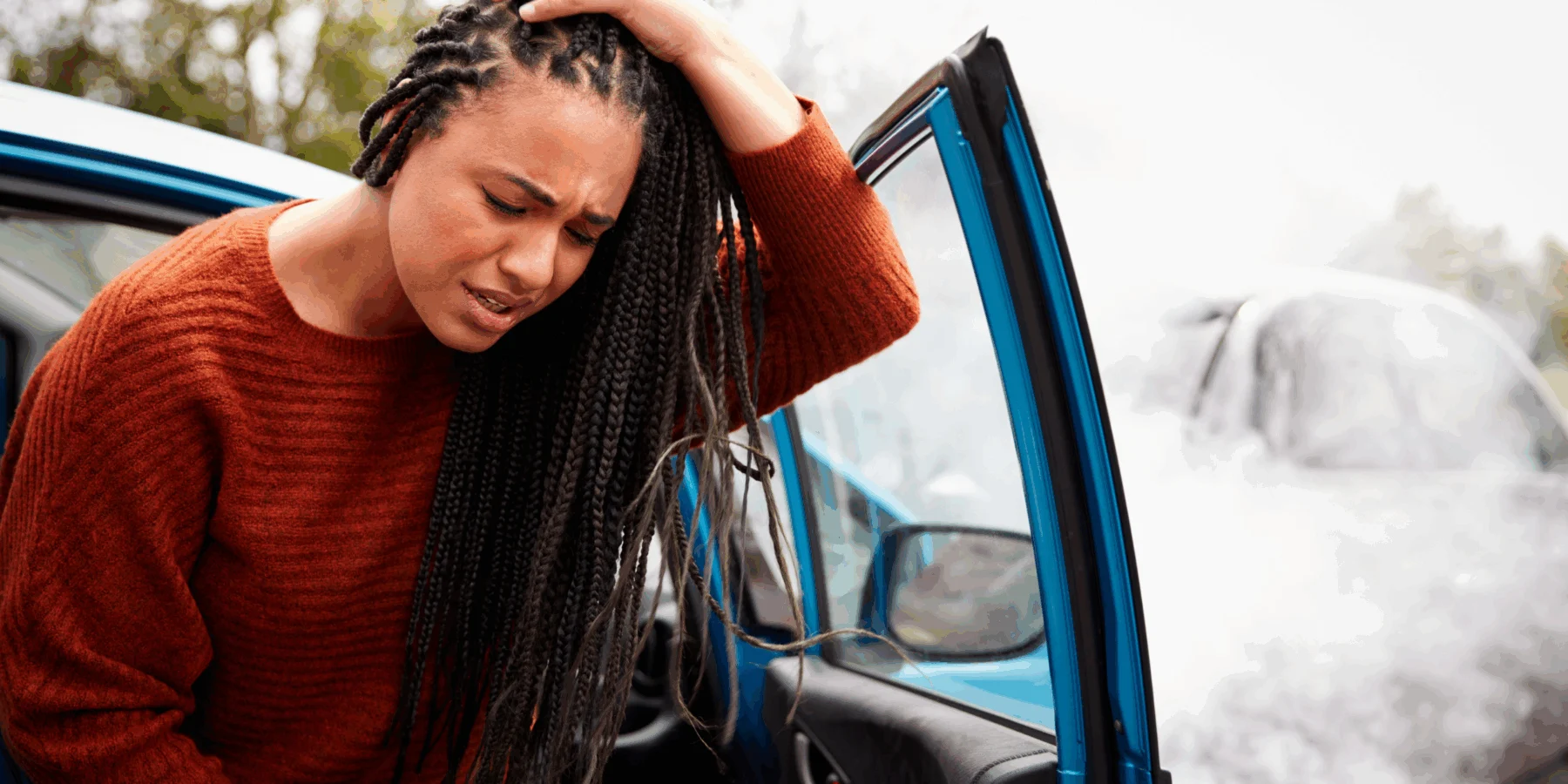 Distressed woman holding her head beside an open car door